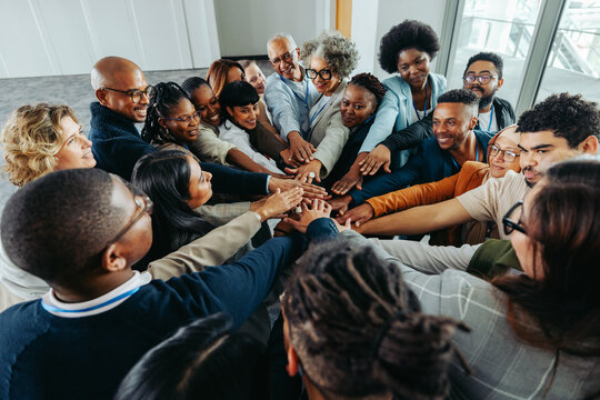 Teamwork and unity in business with multiethnic colleagues joining hands together