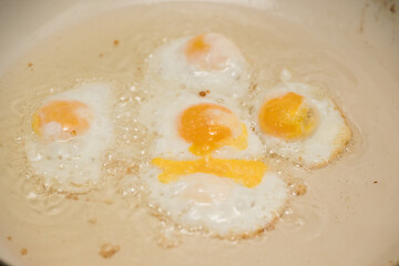 Chicken egg and 9 quail eggs in frying pan.
