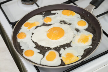 Chicken egg and 9 quail eggs in frying pan.