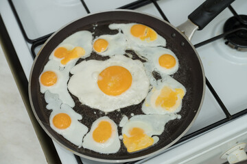 Chicken egg and 9 quail eggs in frying pan.