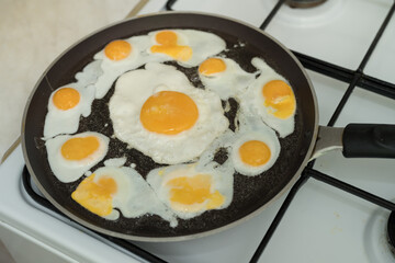 Chicken egg and 9 quail eggs in frying pan.