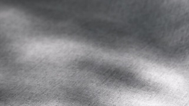 Smooth gray fabric waves and flows, creating elegant folds and ripples, illuminated by soft light, showcasing its delicate texture and movement