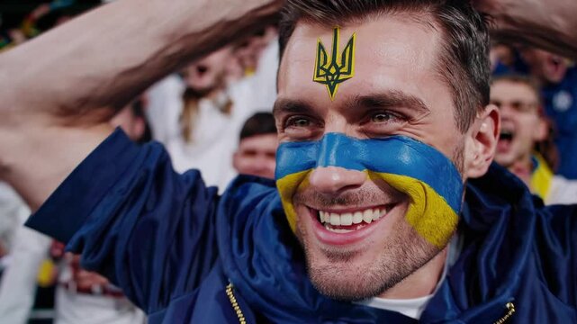 Proud Ukrainian sports fan with bold flag face paint and trident symbol at a stadium  
