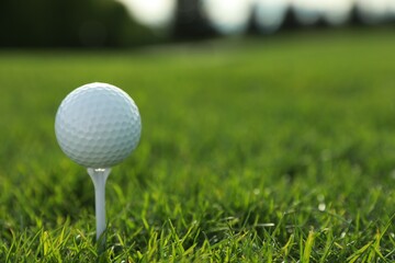 Golf ball on tee at green course, closeup. Space for text