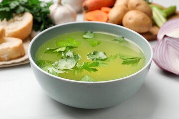 Tasty chicken bouillon in bowl on white table, closeup