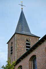Fototapeta premium A countryside church tower with a spire and cross against a blue sky