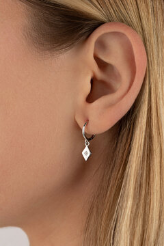 Close-up of female caucasian ear with elegant silver earring. Jewelry catalog. 