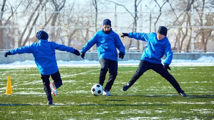 Youth football team practicing movement strategy, positioning, and teamwork on cold outdoor field....