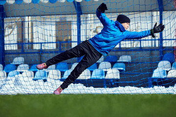 Last-Second Block. Boy lunging toward ball, making crucial attempt to block shot, emphasizing importance of perseverance and defensive skills. Concept of goalkeeping, sports moment.