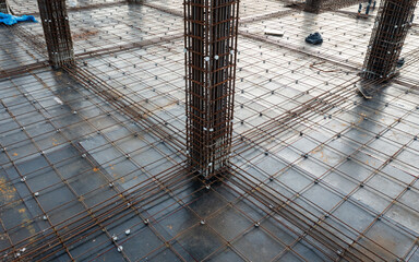 aerial view of a construction site floor, showing a grid of steel rebar, reinforced concrete...