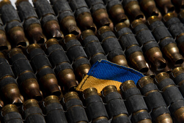 the concept of war in Ukraine. Flag of Ukraine as if drowning among weapons