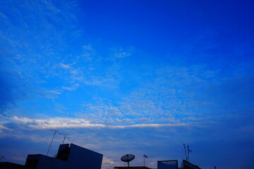 Dramatic sunset sky with clouds and silhouettes. A vibrant blue sky with fluffy white clouds