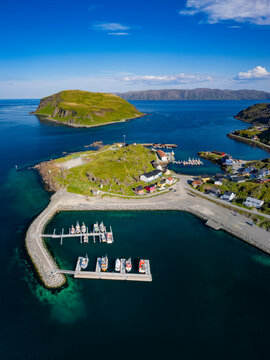 Aerial view of a picturesque traditional village with houses and fishing boats by the tranquil coastline, Kamoyvaer, Mageroy Island, Finnmark, Norway.