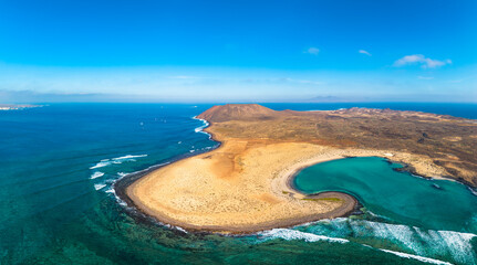 Aerial view of volcanic coast with sandy beach and clear blue sea, Lobos Island, Canary Islands, Spain.
