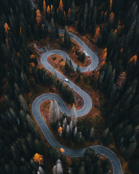 Aerial view of a winding road through vibrant autumn foliage in the Dolomites, Cortina d'Ampezzo, Provinz Belluno, Italy.