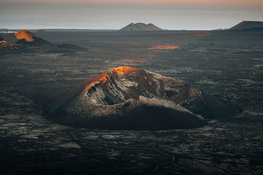 Aerial view of dramatic volcanic landscape at sunset with rugged peaks and barren terrain, Fuente de Montana Negra, Lanzarote, Canary Islands, Spain.