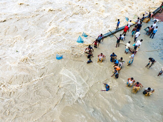 Feni, Bangladesh - 27 August 2024: Aerial view of fishing community struggling in flood waters with handmade nets along Feni River, Chittagong, Bangladesh.
