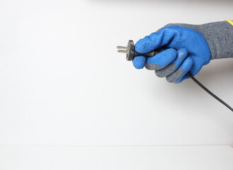 socket plug in the hand in a blue glove