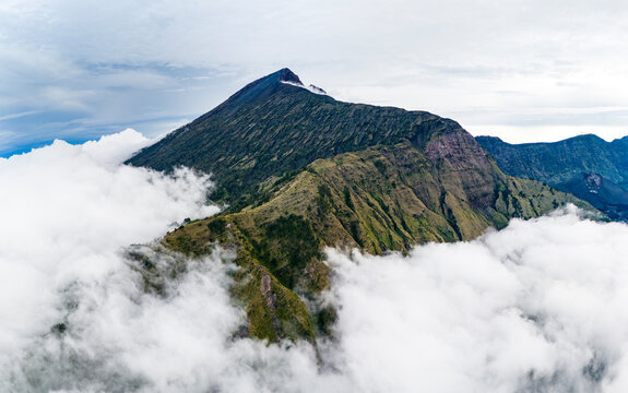 Aerial drone view of the top of active Rinjani volcano above the clouds, island of Lombok, Indonesia