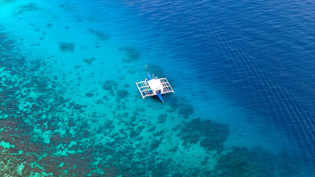 Aerial drone view of fishing boat in vibrant ocean water on the island of Bohol, Philippines