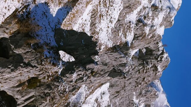 Aerial view of the snowy peaks of Grigna massif, with rocks and snow covering the steep slopes of Alpe Cainallo in winter. vertical video