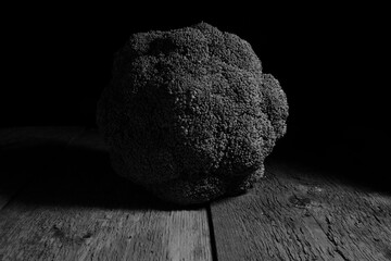 A broccoli in black and white picture with its shope and lots of tones and shadows.