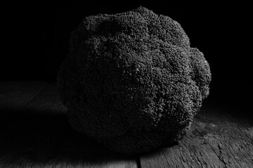 A broccoli in black and white picture with its shope and lots of tones and shadows.