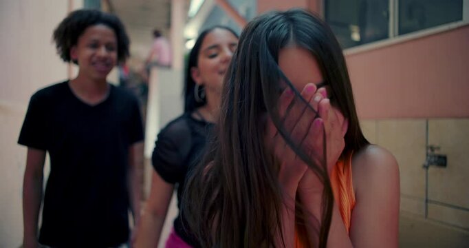 Teenager covering face in distress as friend pulls her hair in mockery and bullying in suburban alleyway, showcasing themes of peer pressure, emotional vulnerability, and youth conflict