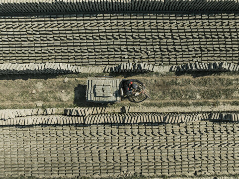 Aerial view of organized brick fields with people working in a factory, Suti Para Union, Dhamrai, Dhaka, Bangladesh.
