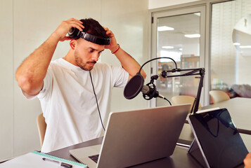 Radio host wearing headphones and preparing for recording podcast in radio station