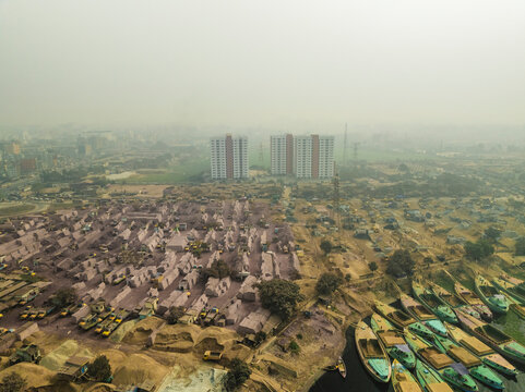 Aerial view of industrial area with cement industries, factories, high rise buildings, and a river with boats, Amin Bazar, Savar, Dhaka, Bangladesh.
