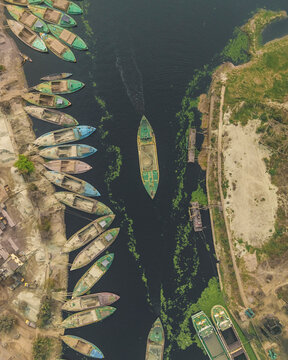 Aerial view of boats on the Buriganga river with cement industries in the background, Amin Bazar, Savar, Dhaka, Bangladesh.