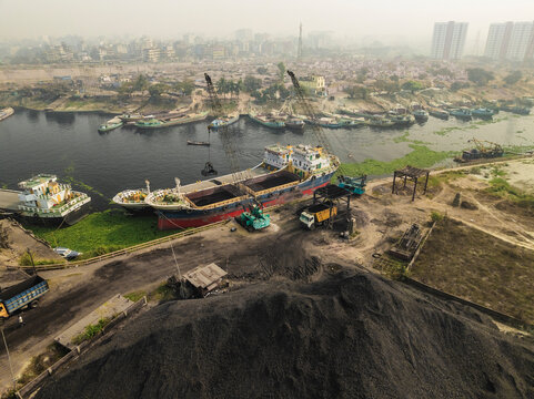 Aerial view of industrial coal factory with ships and river in urban landscape, Amin Bazar, Savar, Dhaka, Bangladesh.
