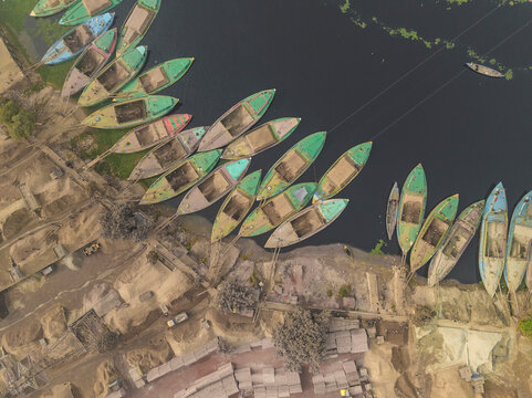 Aerial view of boats moored along the Buriganga river with vibrant cement industries, Darus Salam Thana, Dhaka, Bangladesh.