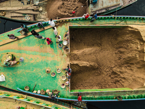 Dhaka, Bangladesh - 02 February 2025: Aerial view of people working with boats along the Buriganga river in a bustling market, Darus Salam Thana, Dhaka, Bangladesh.
