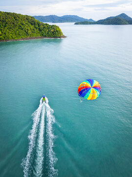 Aerial view of parasailing and a speedboat on the beautiful ocean with a tropical coastline, Kampung Lubok Buaya, Langkawi, Malaysia.