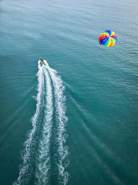 Aerial view of parasailing and boating on a vibrant tropical ocean with waves, Kampung Lubok Buaya, Langkawi, Malaysia.