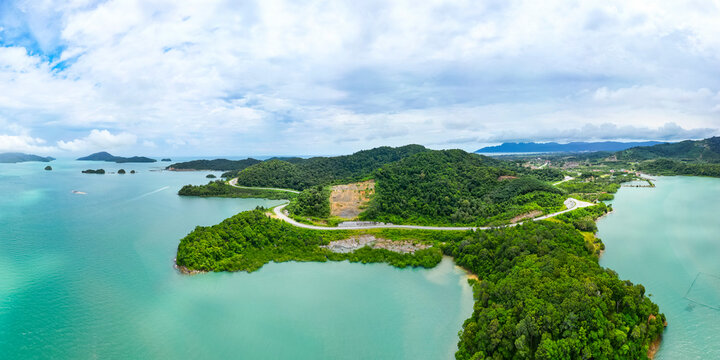 Aerial view of a tropical island with a serene coast, lush greenery, and a winding road, Kampung Lubok Buaya, Langkawi, Malaysia.