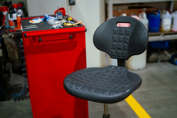 Darker grey creeper chair. Industrial mechanic workshop chair. Rotating mechanics chair in garage...