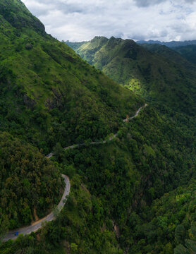 Aerial view of lush mountainous landscape with a winding road through greenery, Ella, Badulla District, Sri Lanka.