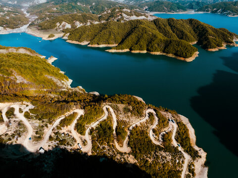 Aerial view of serene Bovilla Lake surrounded by majestic mountains and a winding road, Herraj, Tirana, Albania.
