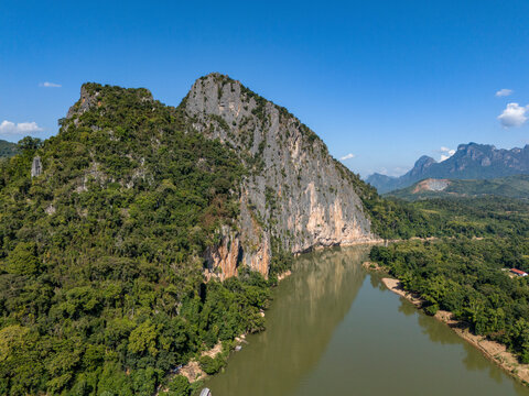 Aerial view of pak ou caves area with serene limestone rock formations, lush greenery, and a winding river, Pak Ou District, Luang Prabang, Laos.