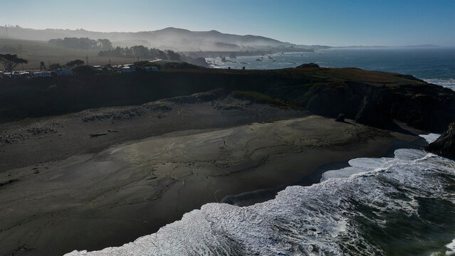 Aerial view of black sand beach with waves and fog, Bodega Bay, California, United States.