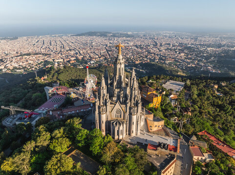 Aerial view of beautiful historic cityscape with a prominent cathedral surrounded by greenery and hills, Sarria, Barcelona, Spain.
