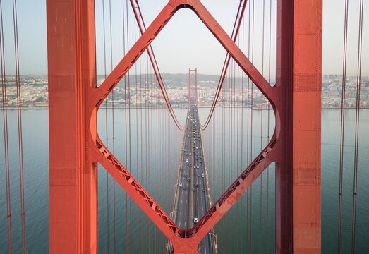 Aerial view of the iconic red Ponte 25 de Abril suspension bridge spanning the river in a vibrant urban landscape, Lisbon, Lisbon, Portugal.
