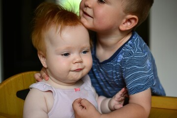 Toddler boy is hugging his little baby sister. Brother and sister love and strong bond. Concept siblings love .
