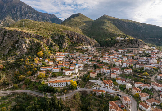 Aerial view of picturesque village nestled in serene mountains with charming houses and winding road, Dhermi, Vlore, Albania.