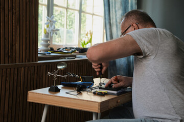 Men wearing denim shirt working with electronic components at his home office