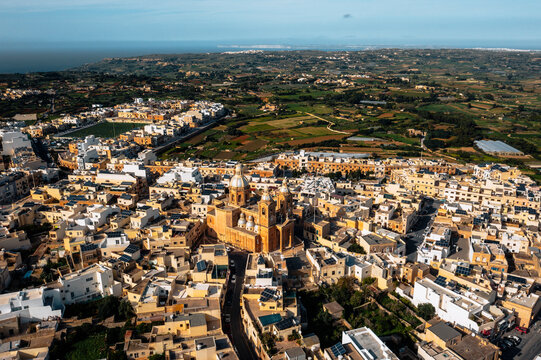 Aerial view of the historic parish church of Mellieha surrounded by colorful rooftops and scenic landscape, Dingli, Malta.