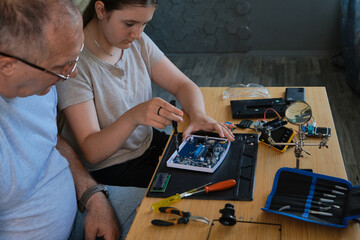 Grandfather and granddaughter work together on an electronics project